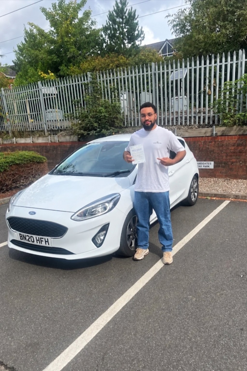 Pupil with a pass certificate beside the white learner car